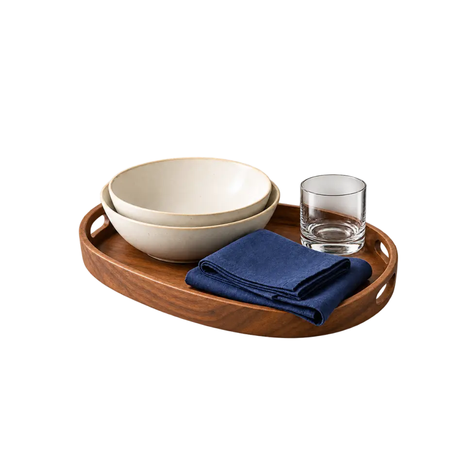 A wooden serving tray with ivory bowls, folded indigo napkins and a clear water glass.